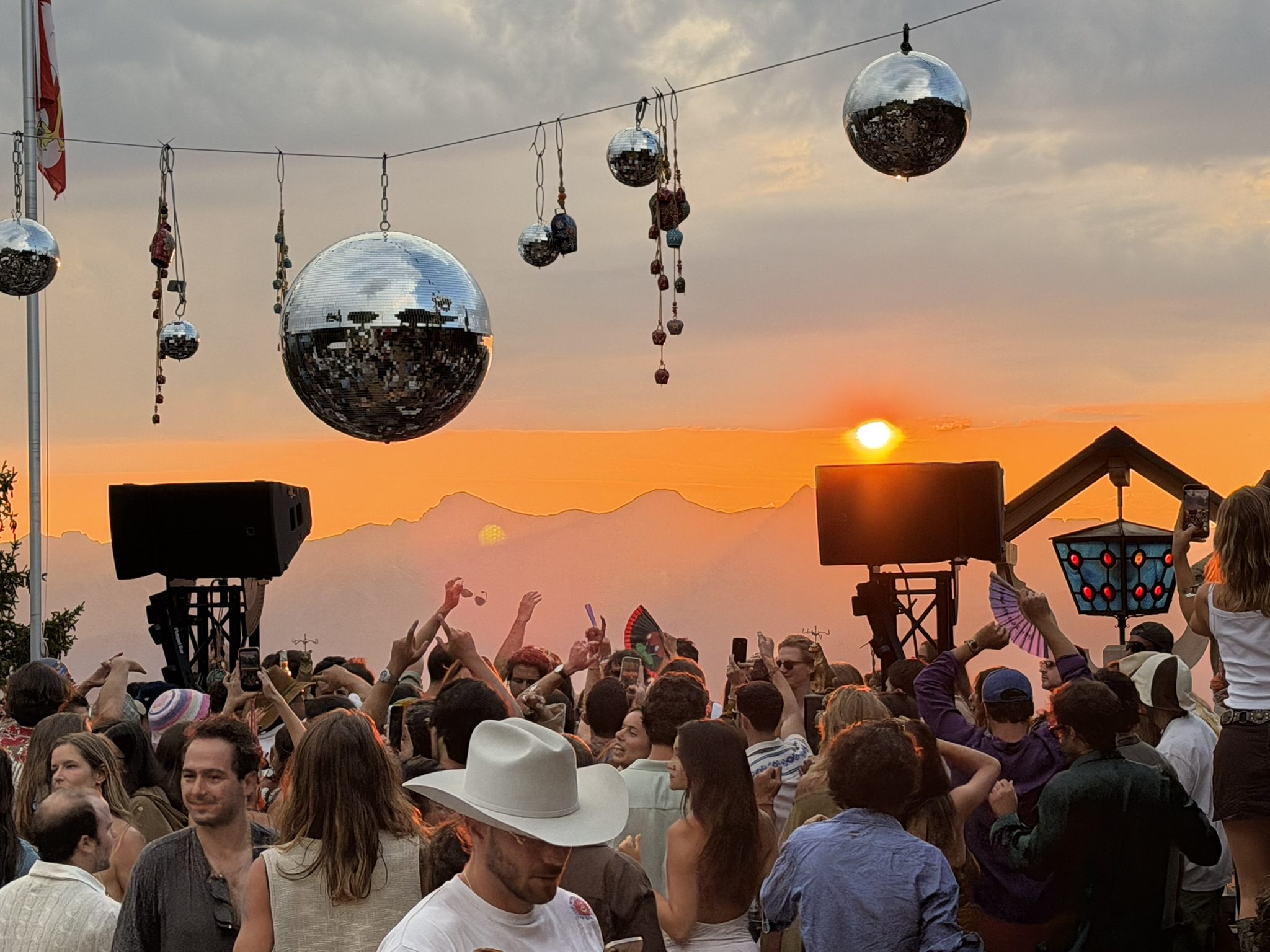 Dancing under disco balls as the sun sets over the mountains